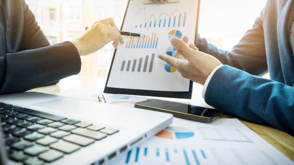 Business professionals reviewing data on a tablet, illustrating real-time monitoring and product traceability enabled by blockchain technology.