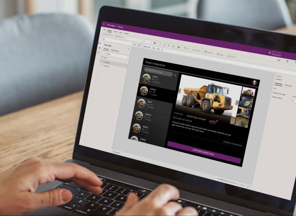 Person using a laptop displaying a dark-themed application interface featuring construction machinery, team member profiles, and related content.