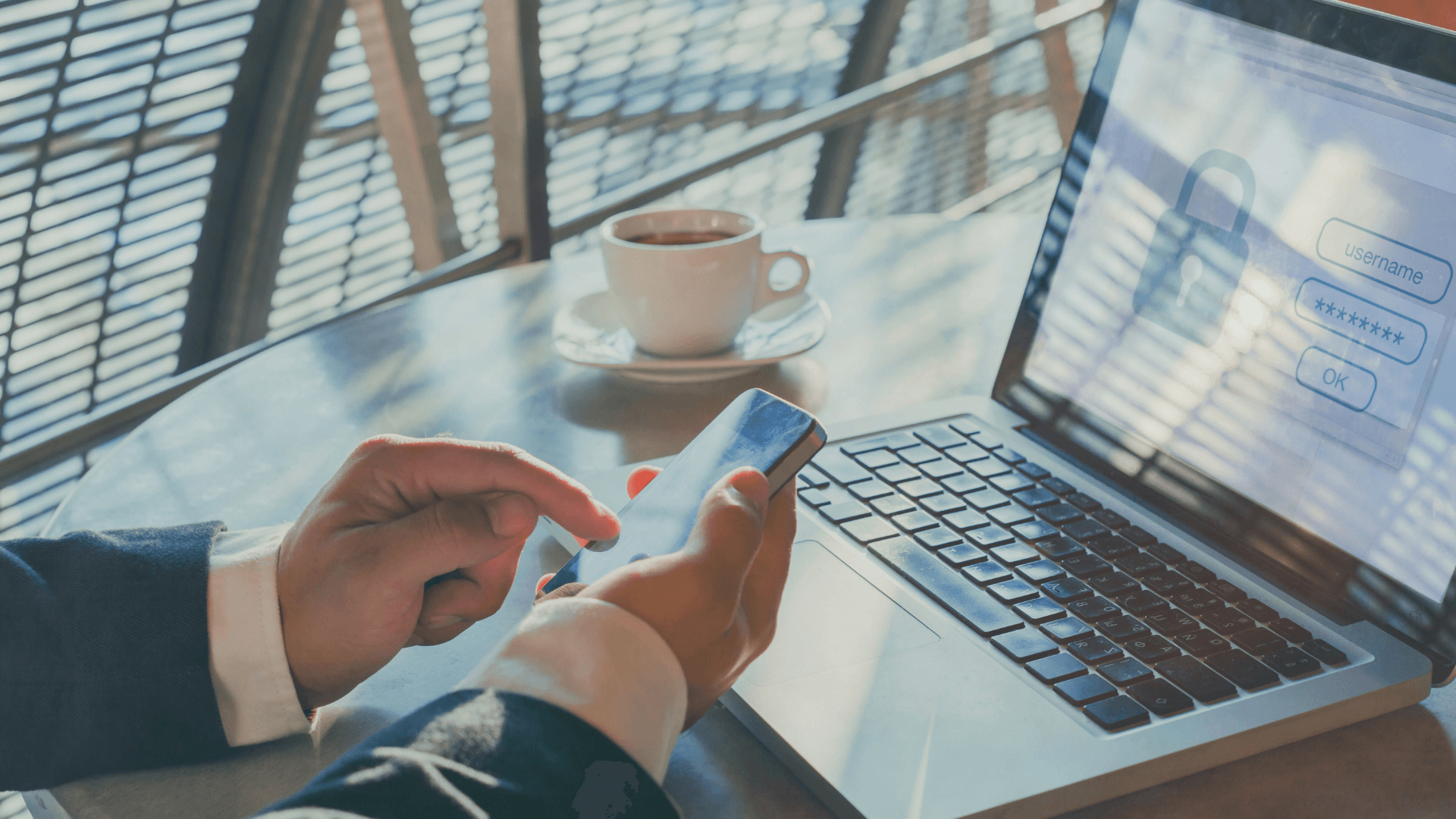 Person using a smartphone next to a laptop displaying a login screen with username and password fields, representing secure access with MFA.
