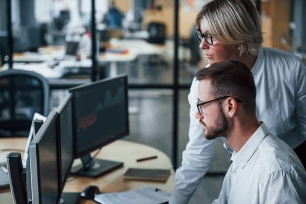 Two professionals in an office looking at a computer screen, representing data analysis for the 2024 Stack Overflow Annual Survey.