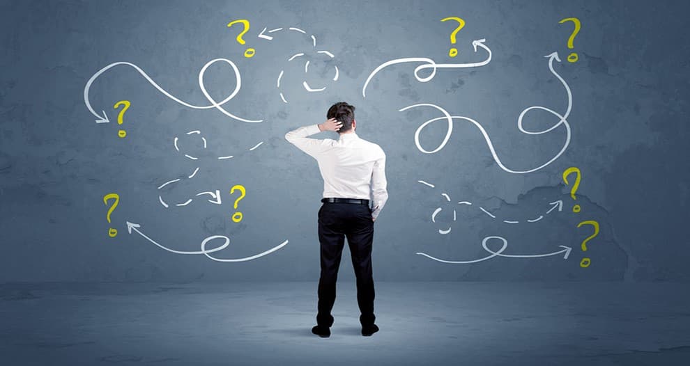 Person standing in front of a wall filled with question marks and arrows, symbolizing decision-making and complexity in multi-tenant environments.