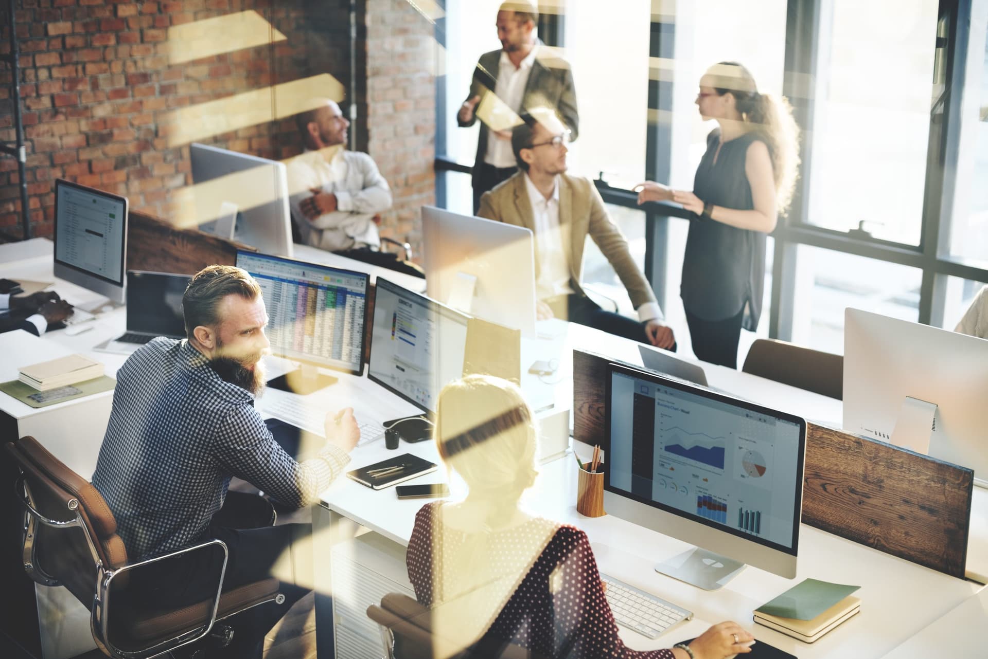 Equipo colaborando en un entorno de oficina moderno, con pantallas que muestran datos y gráficos, representando la adopción de Microsoft Viva para mejorar la experiencia del empleado