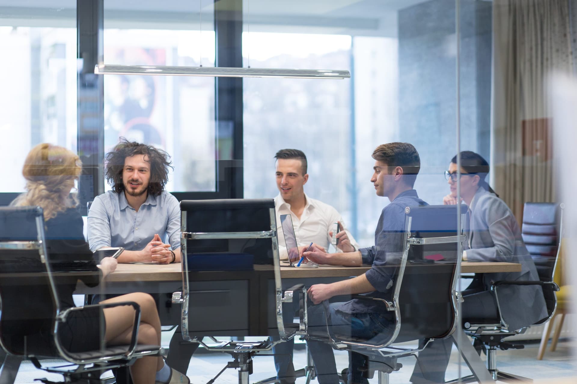 grupo-jovenes-empresarios-discutiendo-plan-negocios-edificio-oficinas-inicio-moderno-scaled.jpg