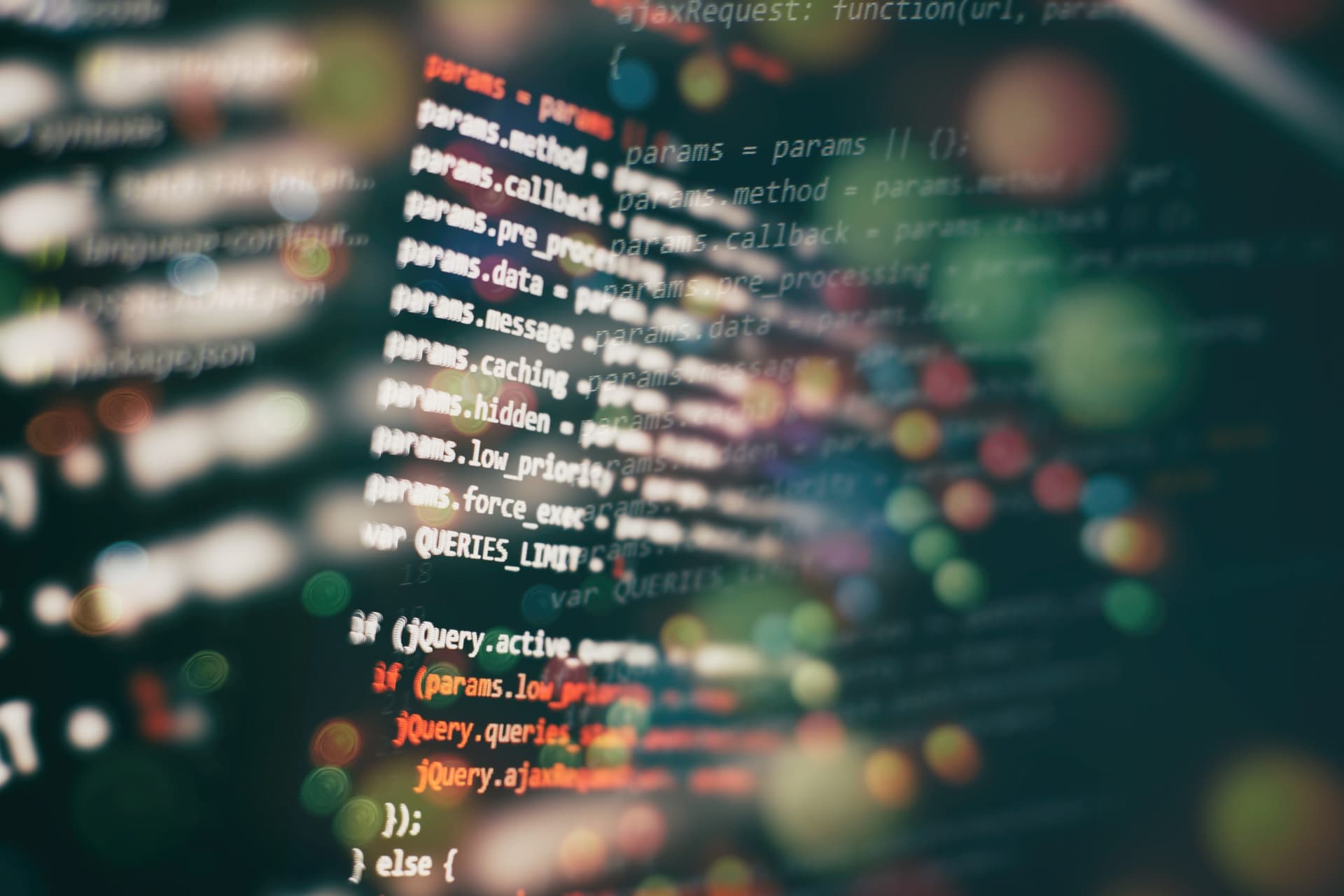 Close-up of a computer screen displaying JavaScript code with syntax highlighting and a colorful bokeh background.