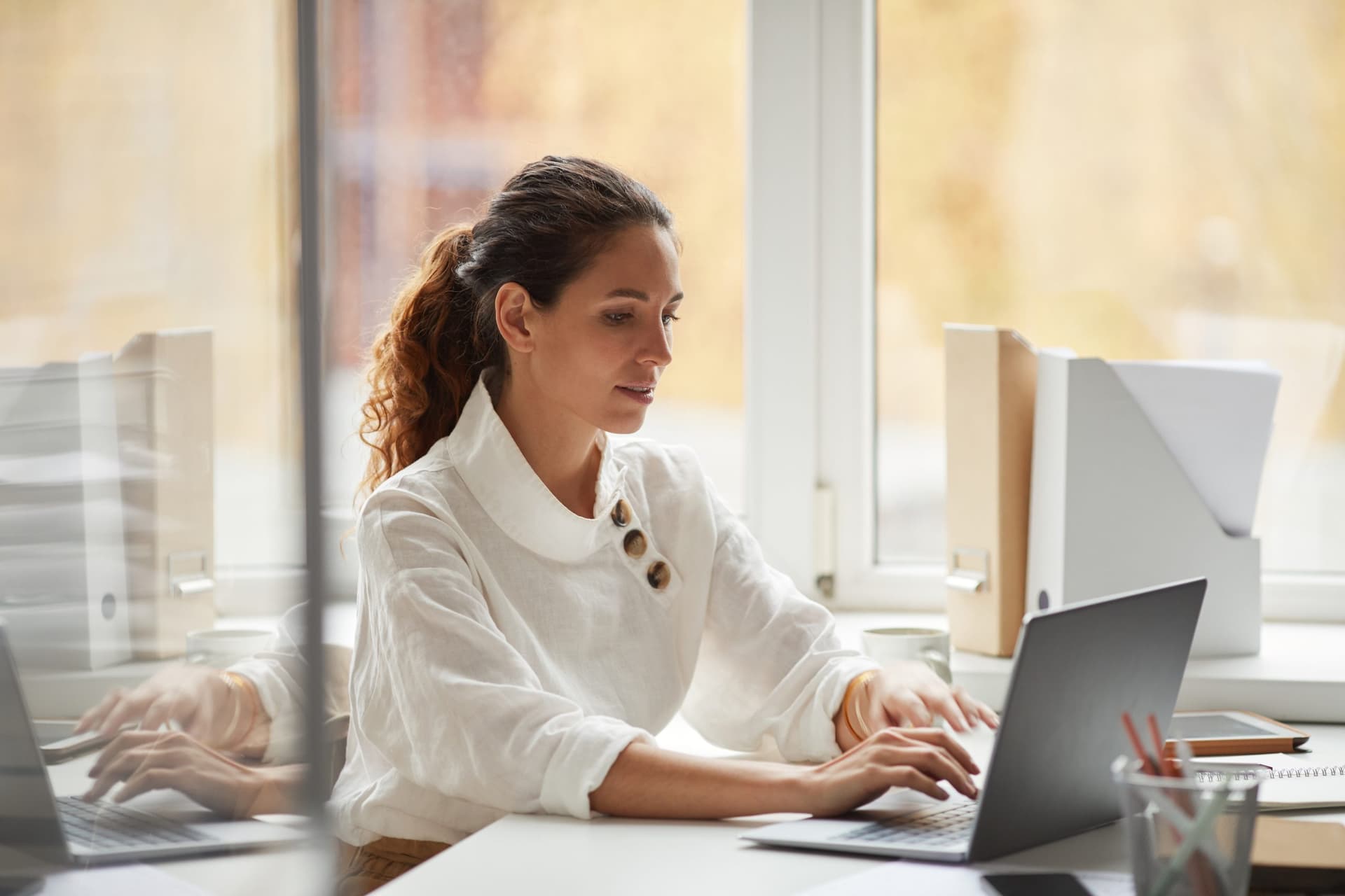 Person working on a laptop at a desk in a bright office setting, representing productivity and low-code application development with Power Apps.